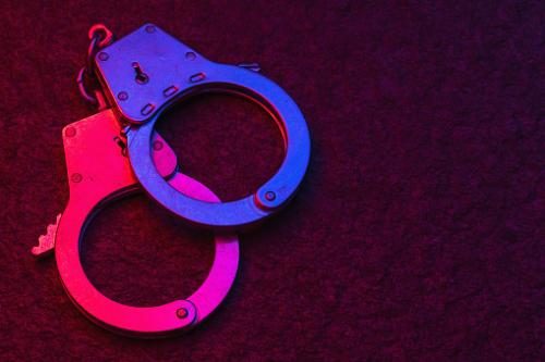 handcuffs-on-dark-background-illuminated-by-flashing-lights-of-police-picture-id1288257264